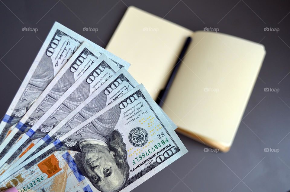 Dollars on the table with a notebook