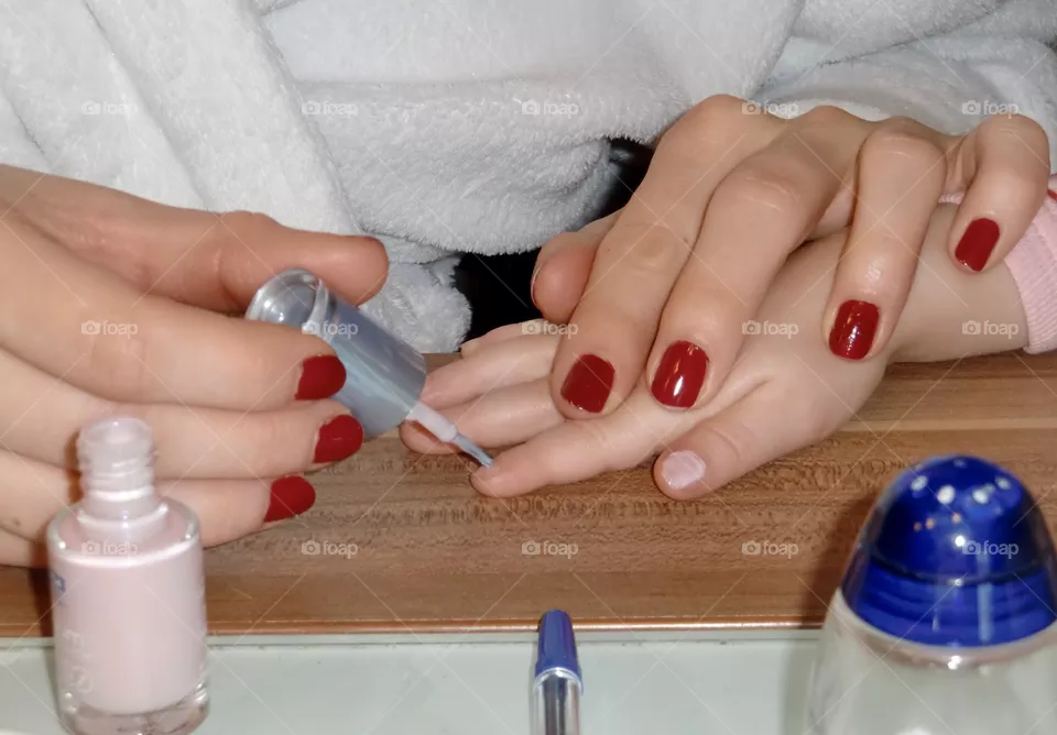 Mother painting the fingernails of her daughter 