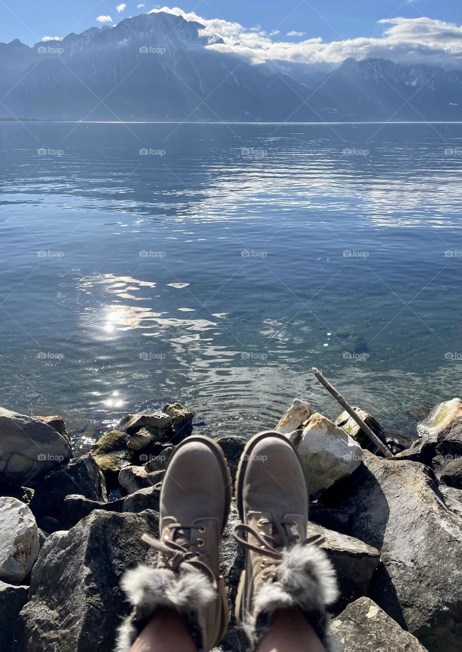 a sunny day at the lake, mountain boots in the foreground with an alpine lake and mountains in the background