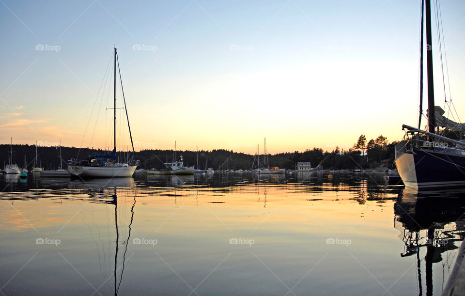 Sailboats float quietly in the calm before sunset