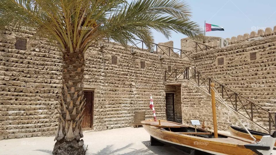 Fort Dubai palm tree pleasant day building stone built boat tree dates flag stairs rod beautiful sky museum