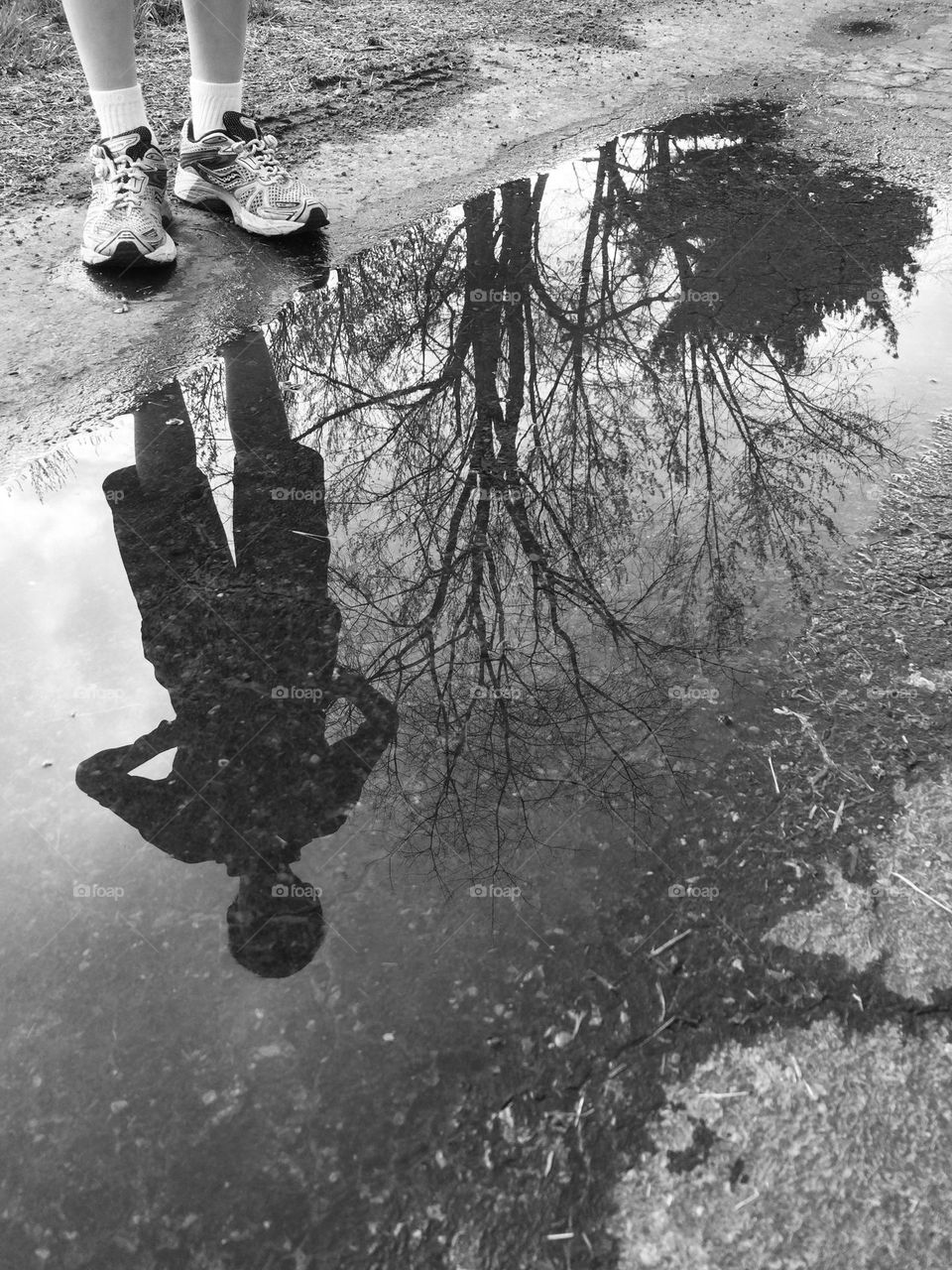 Reflection of a boy into a water puddle