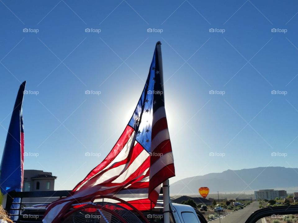 Sun behind American flag, balloon chase truck