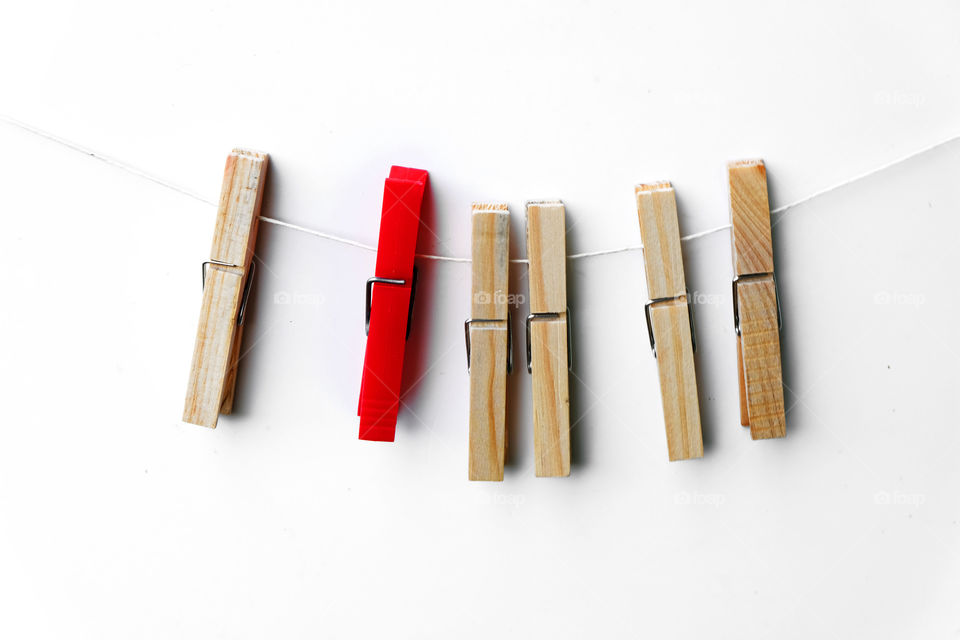 Red clothespin among wooden ones. conceptual diversity photography.
