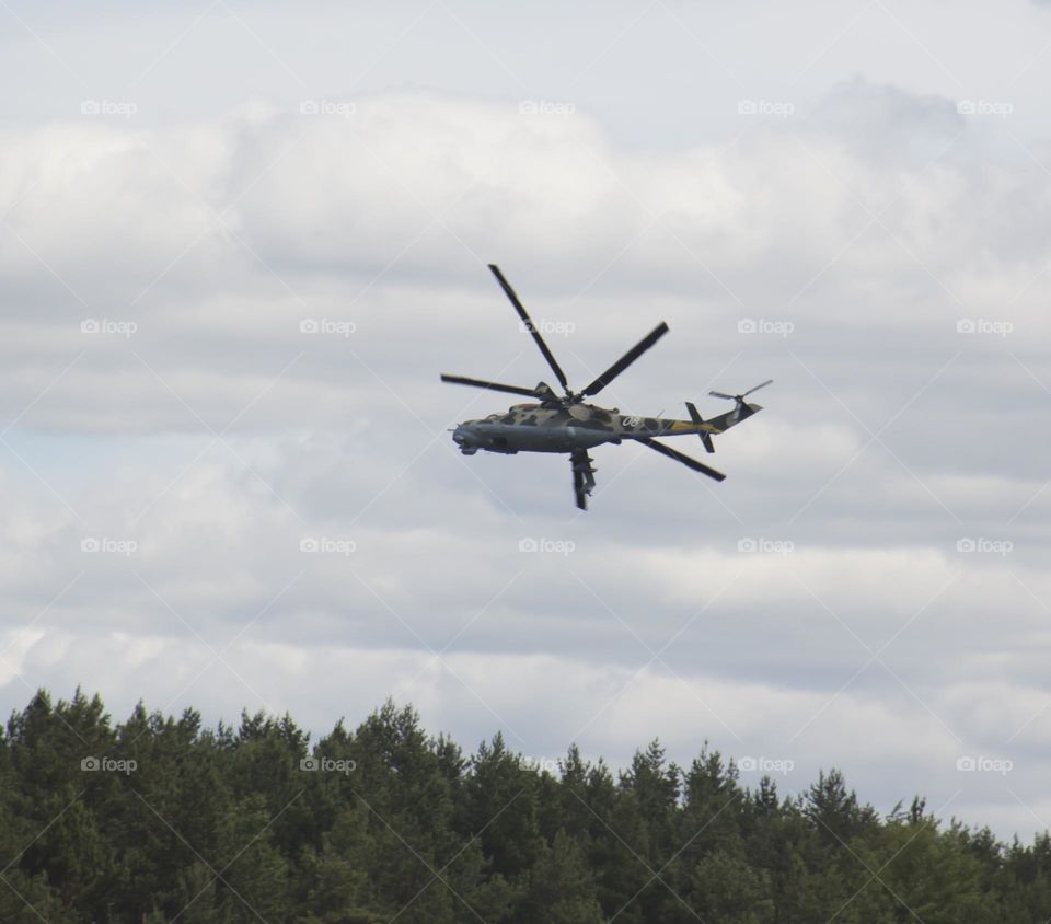 The helicopter is flying against the blue sky.
