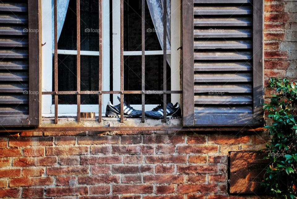 Shoes on a sill. Black and white soccer shoes are talked on the outside of the windowsill in Sienna 