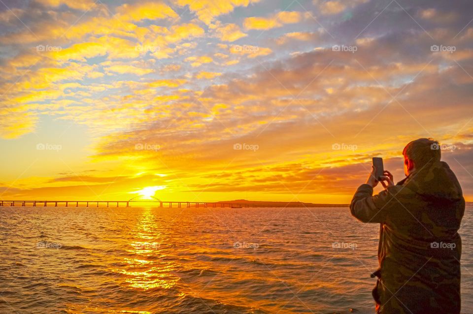 The guy takes a photo of the bridge against the backdrop of the sunset.