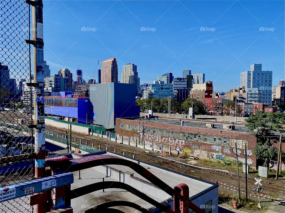 This is the view from the top of the staircase of the „Pulaski Bridge“ at „Newtown Creek“ in LIC, Queens. We are overlooking the „Long Island Railroad“ „LIRR“ train tracks and LIC as well as „Manhattan“ skyscrapers. 2023. Hypnotic Productions