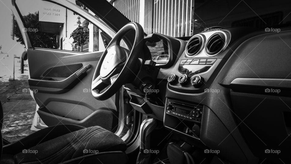 Porta aberta. Carro em preto e branco. Painel, e volante.