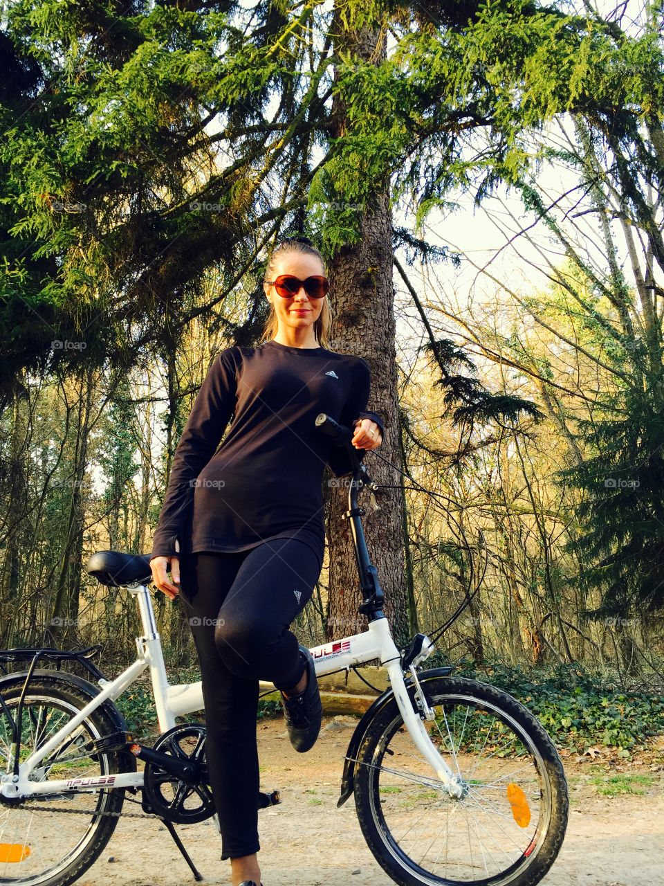 Woman dressed in sportswear standing beside her bicycle