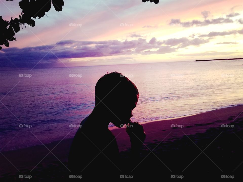 Boy sips on water before beautiful seaside sunset