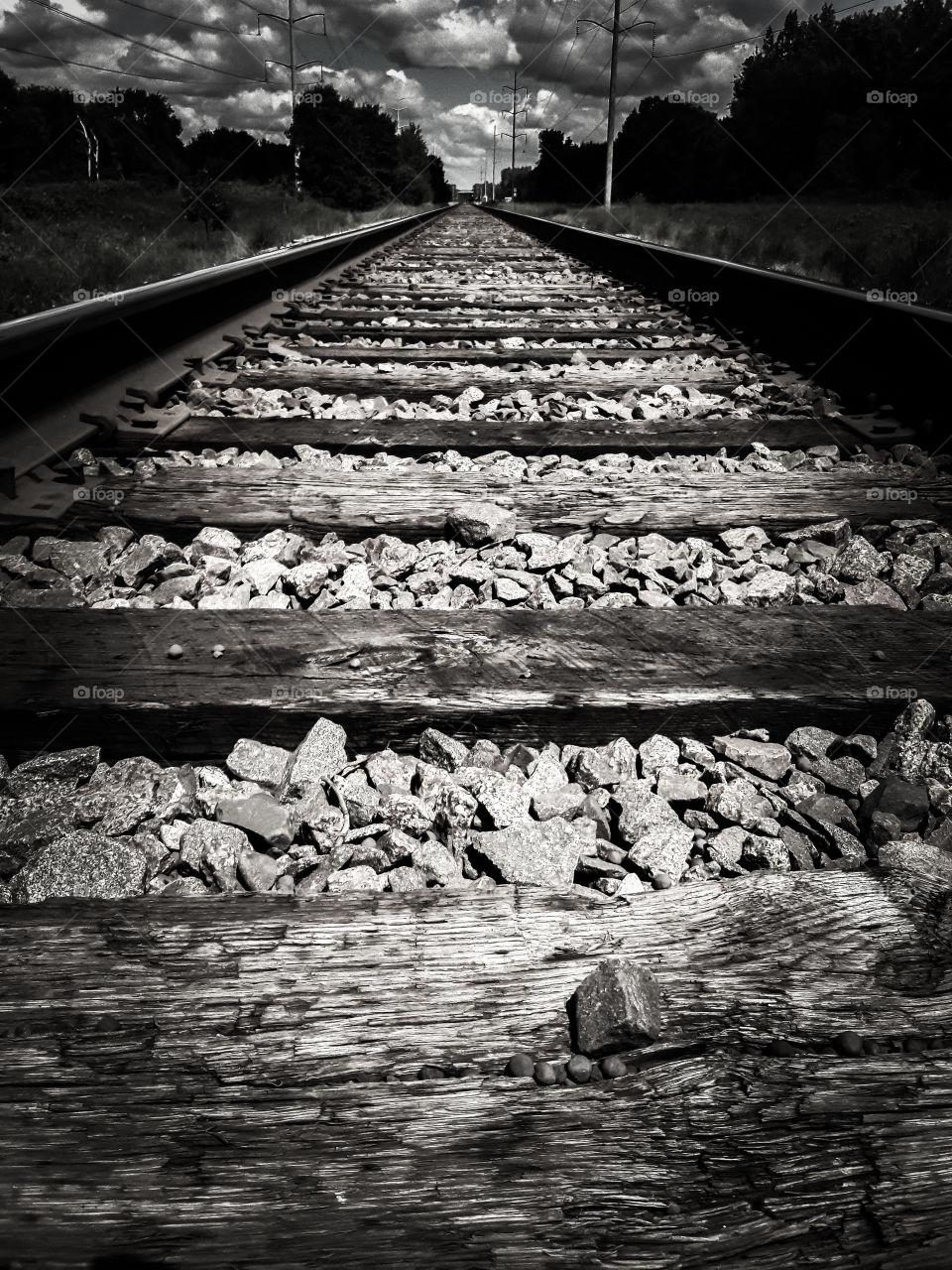 Black and white photograph, looking up the railroad tracks from a low perspective.