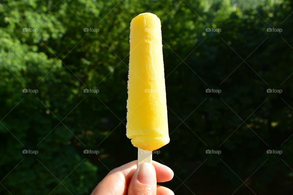 yellow ice cream in the hand green background