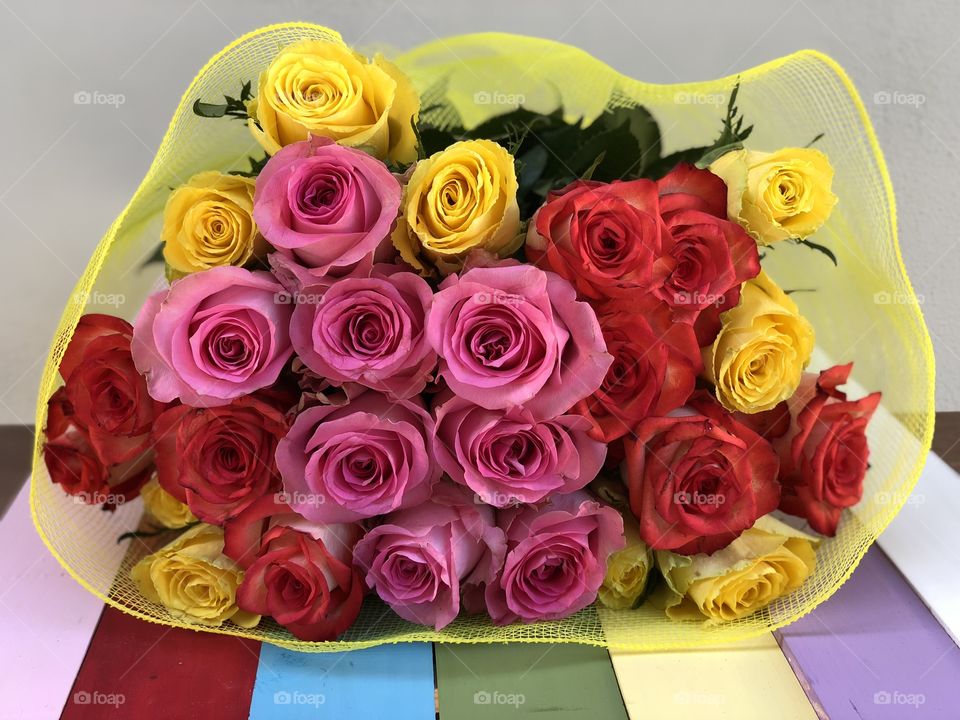 Beautiful bunch or red,pink and yellow roses on a rainbow wooden board