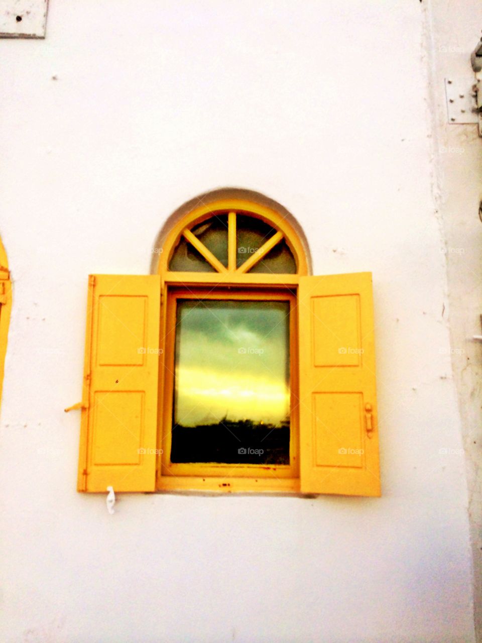Reflections . Sunset reflection through a yellow window in Greece
