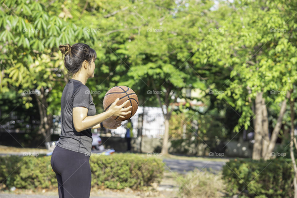 Basketball in hand Asian woman Background blur tree in park.