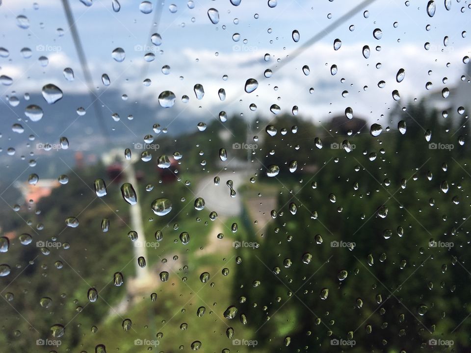 Snapshot on the cable car through rain drop window , out focus to sunny view.