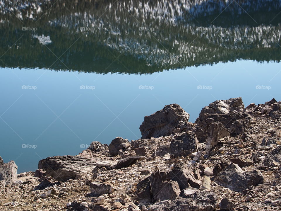 Jagged rocks and boulders along the shoreline of Ochoco Lake in Central Oregon on a sunny spring day.