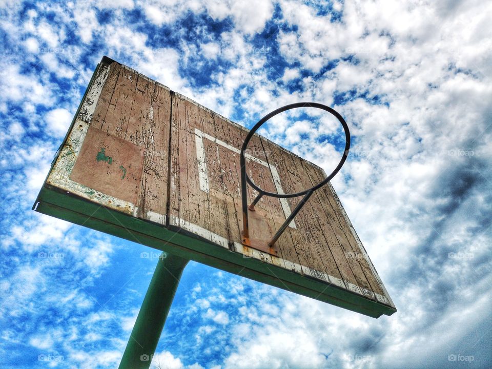 Old basketball hoop against a blue cloudy sky