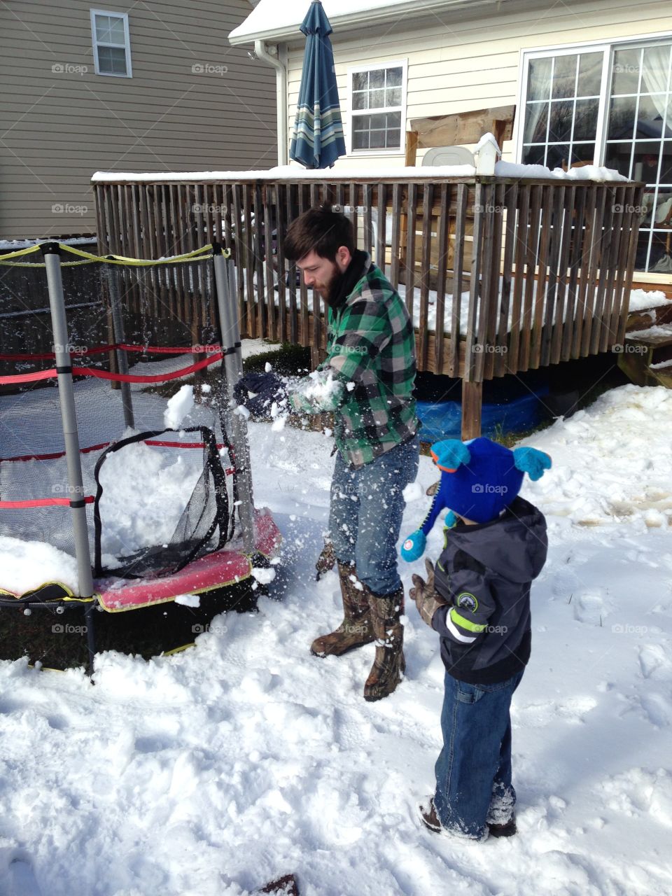 Man and little kid standing near house in snowy weather