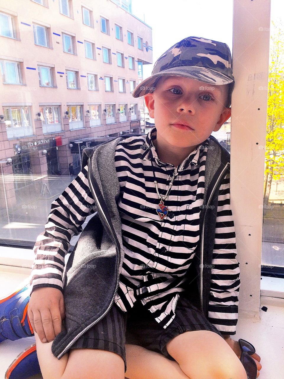 Boy sitting. A cute kid sitting at a window in a big city