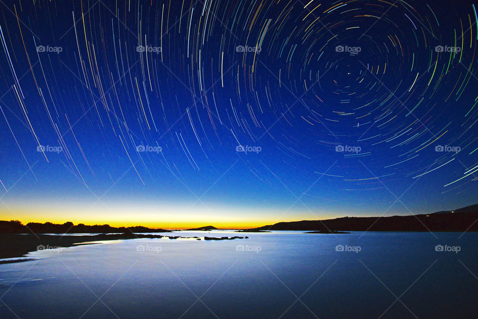 star trail above Elafonissi beach with, on the horizon, the last lights of the sunset that light up the sea