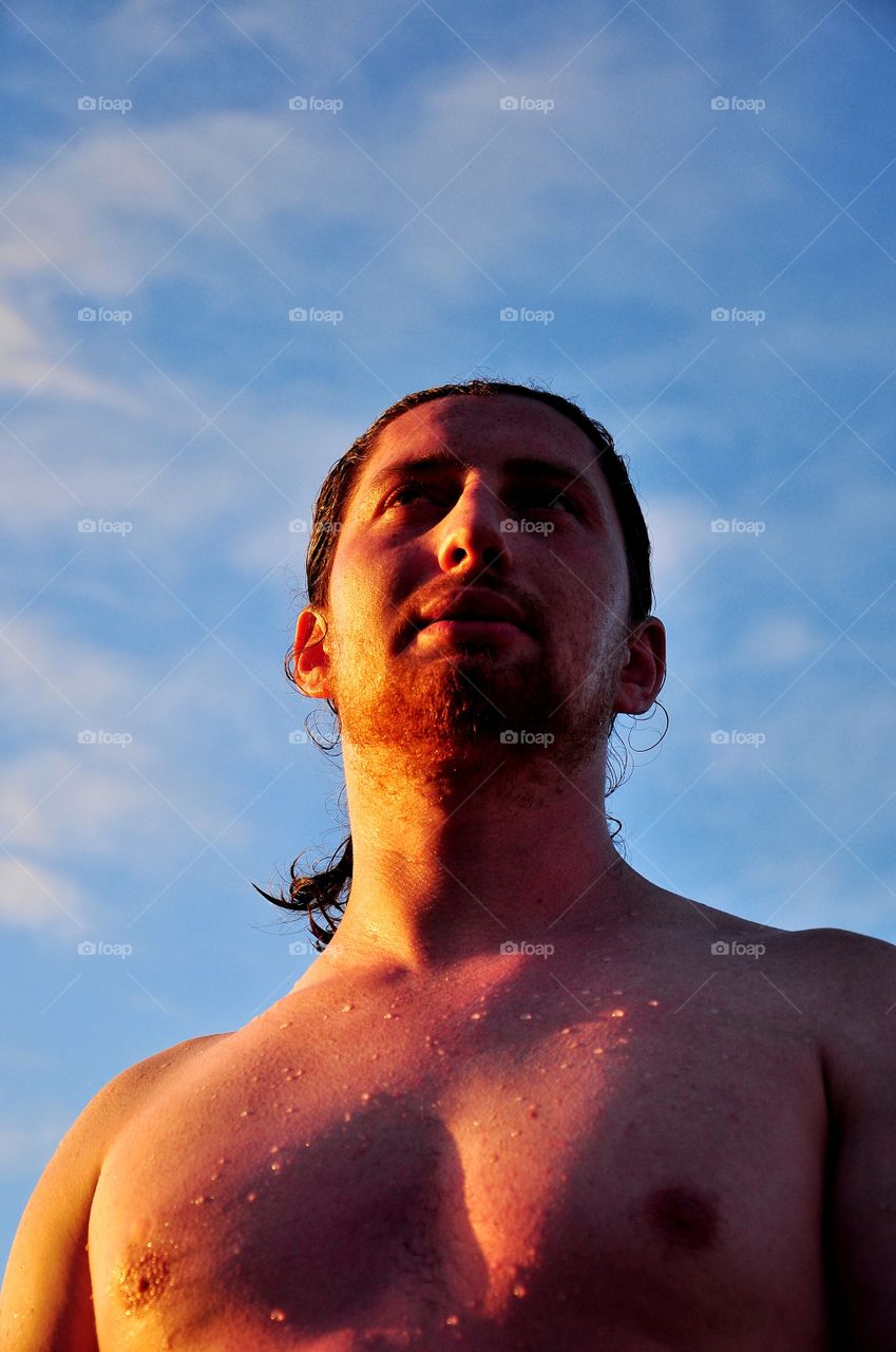 young handsome beard man in the sun rays on the blue sky background