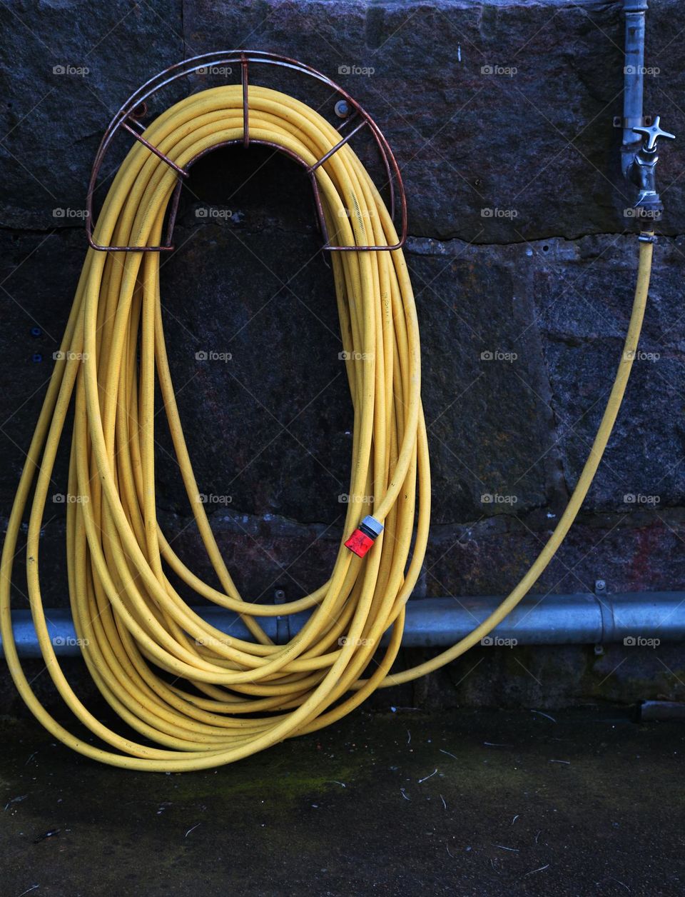 Yellow hose on a stone wall