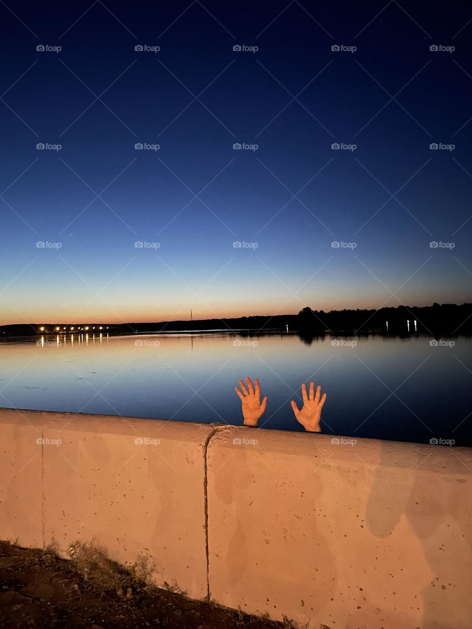 some hands behind the fence near the lake
