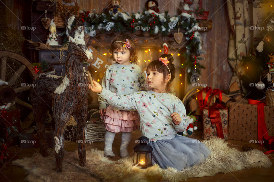 Little sisters near fireplace at Christmas Eve 