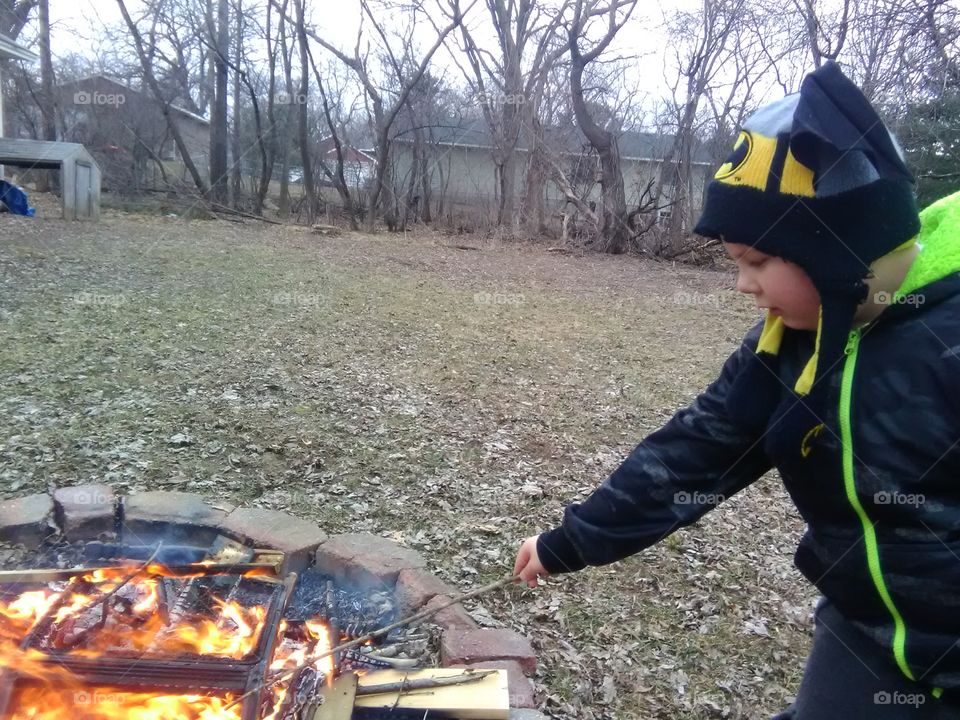 Boy burning stick in fire pit