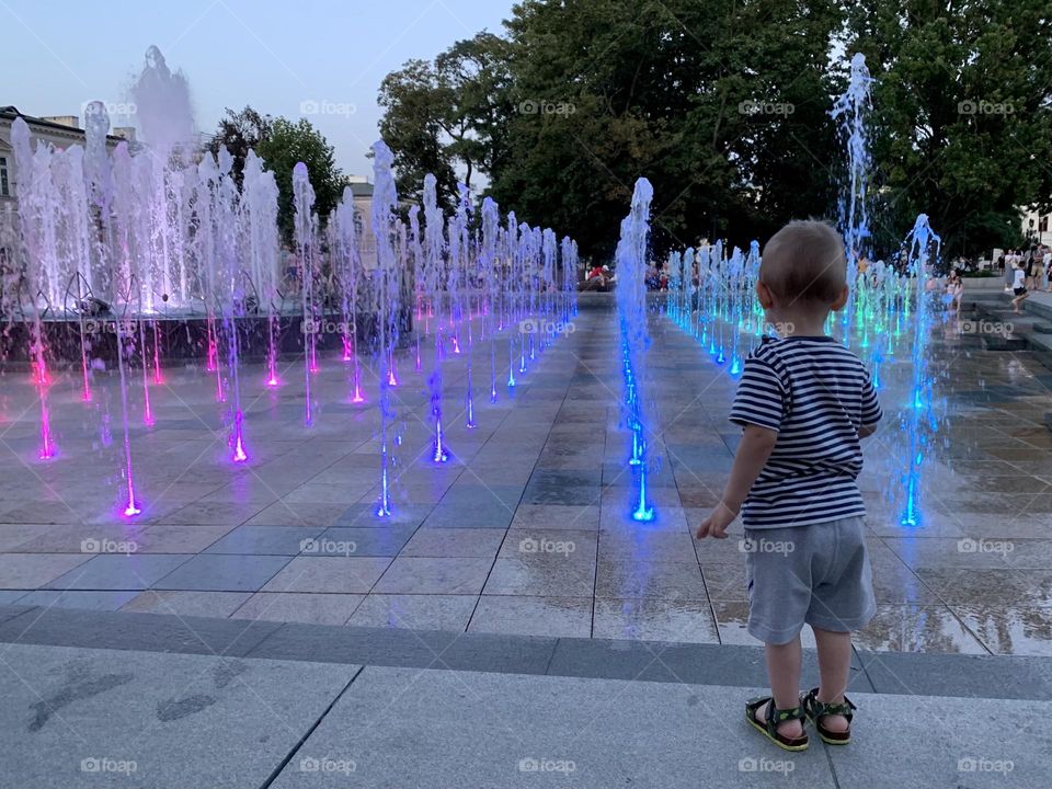 Neon fountain in the evening, boy behind