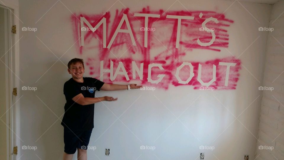 Happy boy showing hangout text on wall