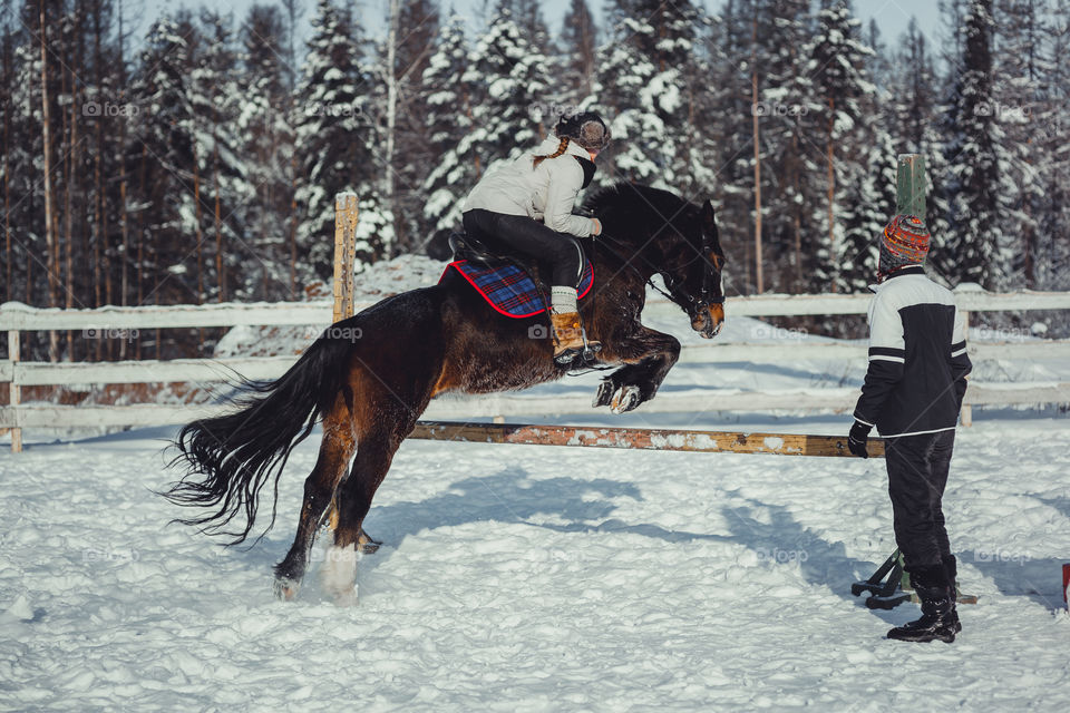 Teenage girl horseback jumping at cold winter day