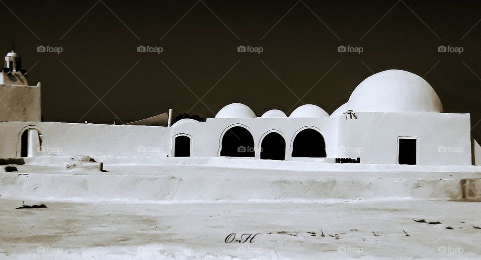 The courtyard of a mosque on the island of Djerba, and the walls are painted white, adding to the beauty of the traditional architecture with its arches