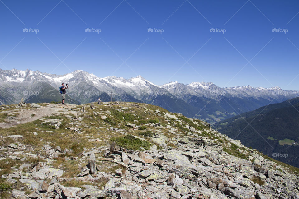 Hiking trail at high altitude in the mountains . Hiker takes a picture of the panoramic view