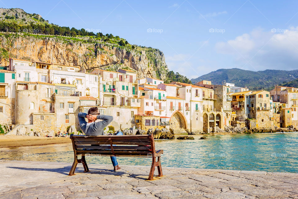 Rear view of man sitting lakeside