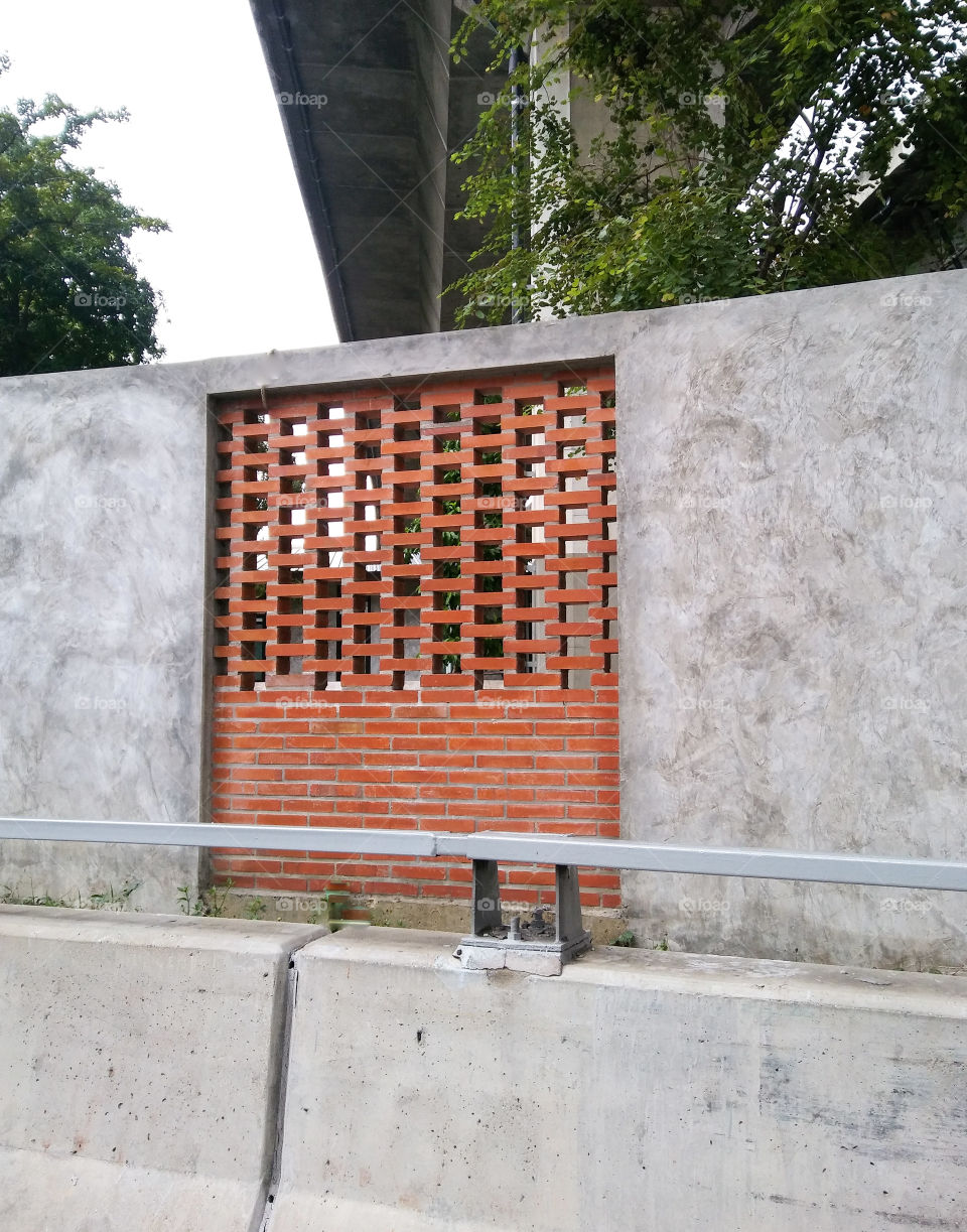 Bricks show and cement wall beside road.