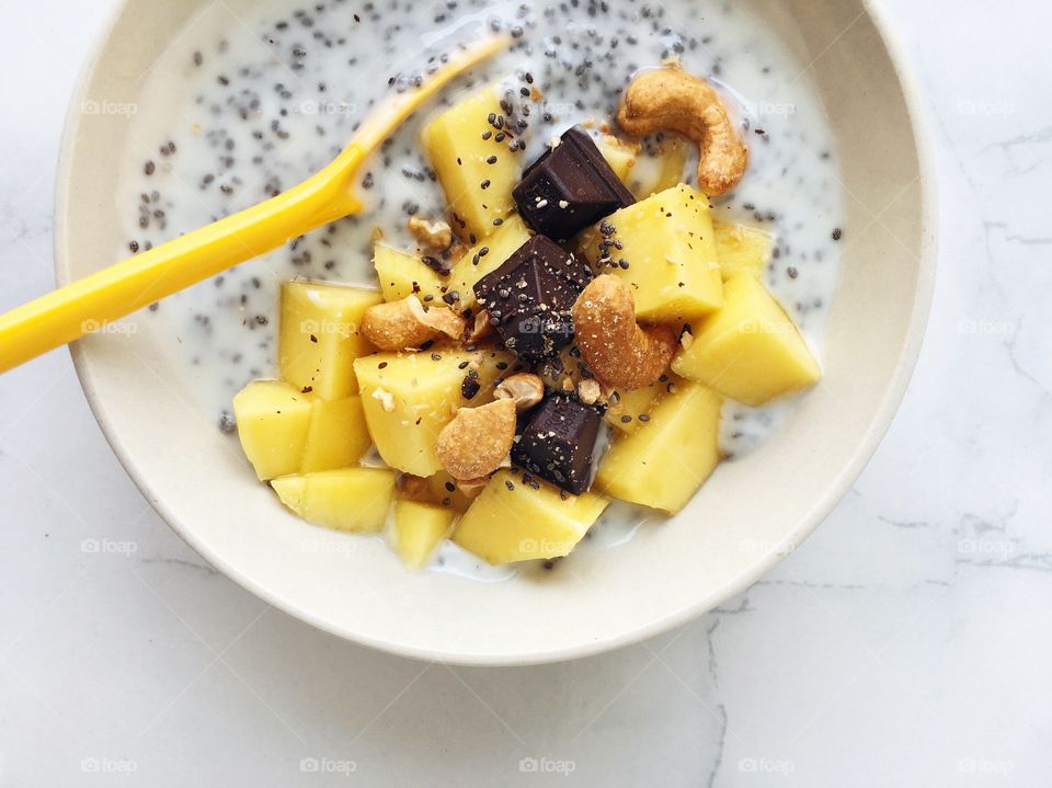 Fresh Fruit Smoothie : Healthy breakfast bowl with mango chia seed, yogurt, dark chocolate and cashew nuts.