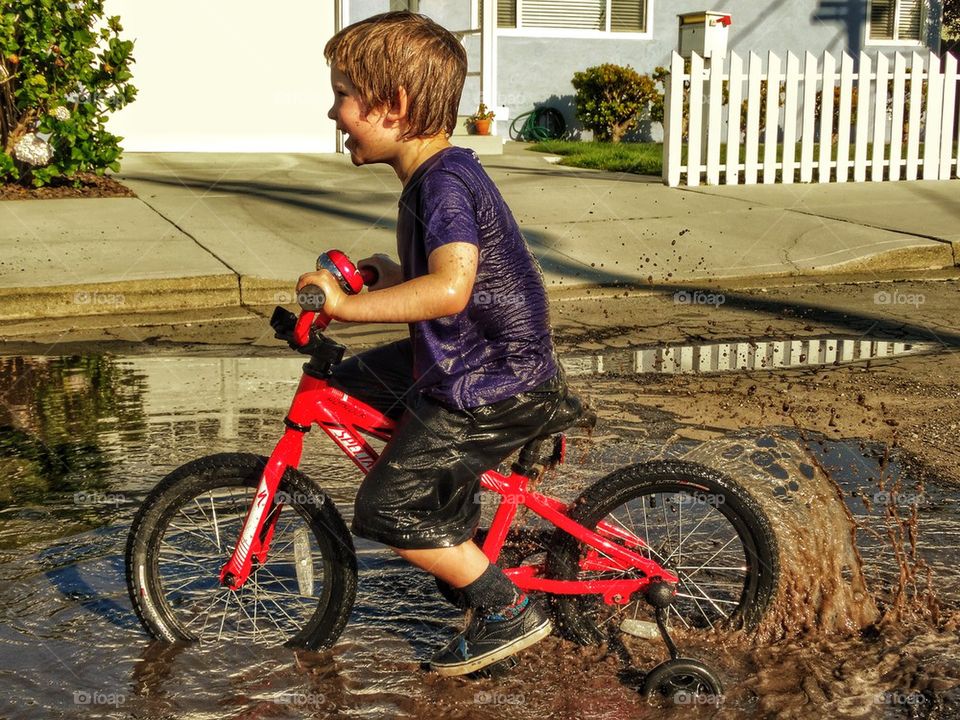 Dirty Boy. Boy Riding His Bike Through A Muddy Puddle
