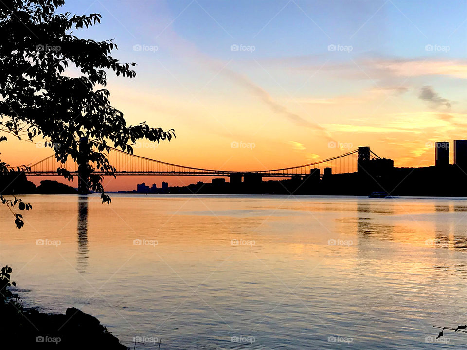 Photo of the Hudson River and the George Washington Bridge at sunset. Taken from Inwood Hill Park in Manhattan. Skyscrapers in New Jersey also seen. 