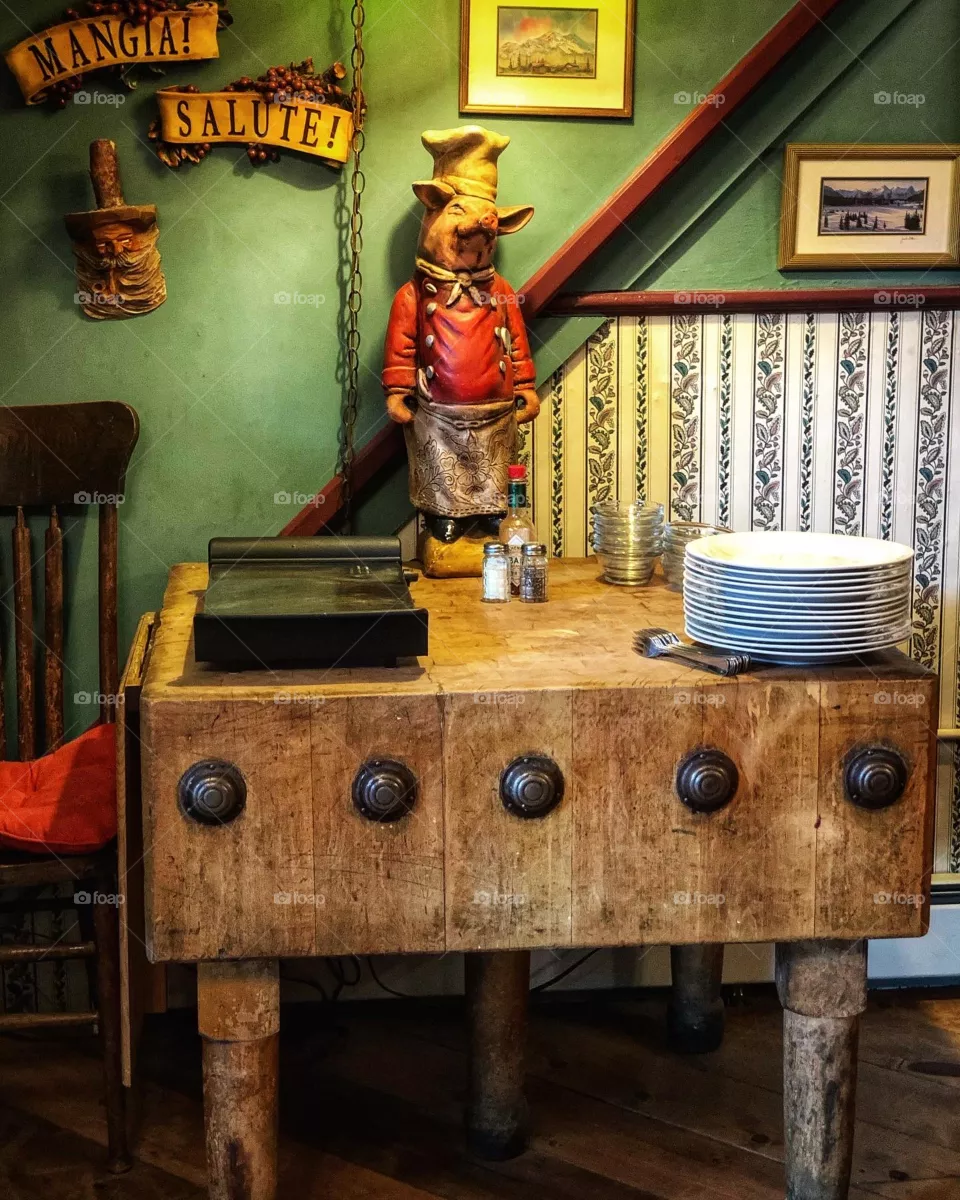 Breakfast set up, vintage butcher block, plates and chef pig. Backdrop color green with wallpaper