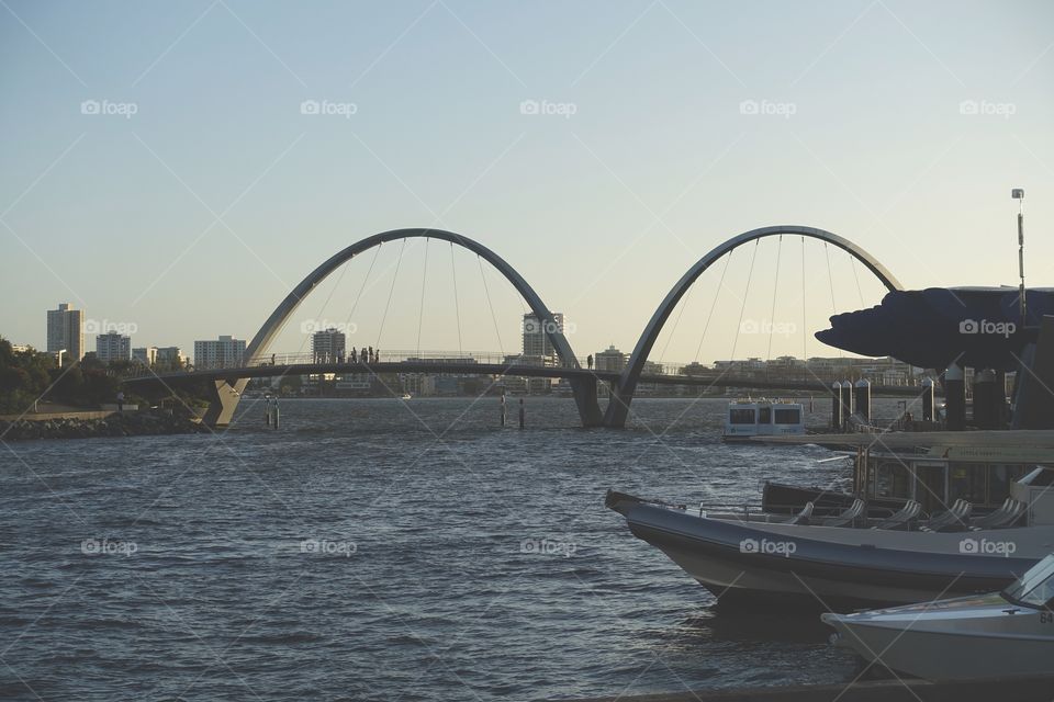 The view of the Swan River, where boats, bridge and skyscrapers can be seen. This place is called Elizabeth Quay, located in Perth, Western Australia.