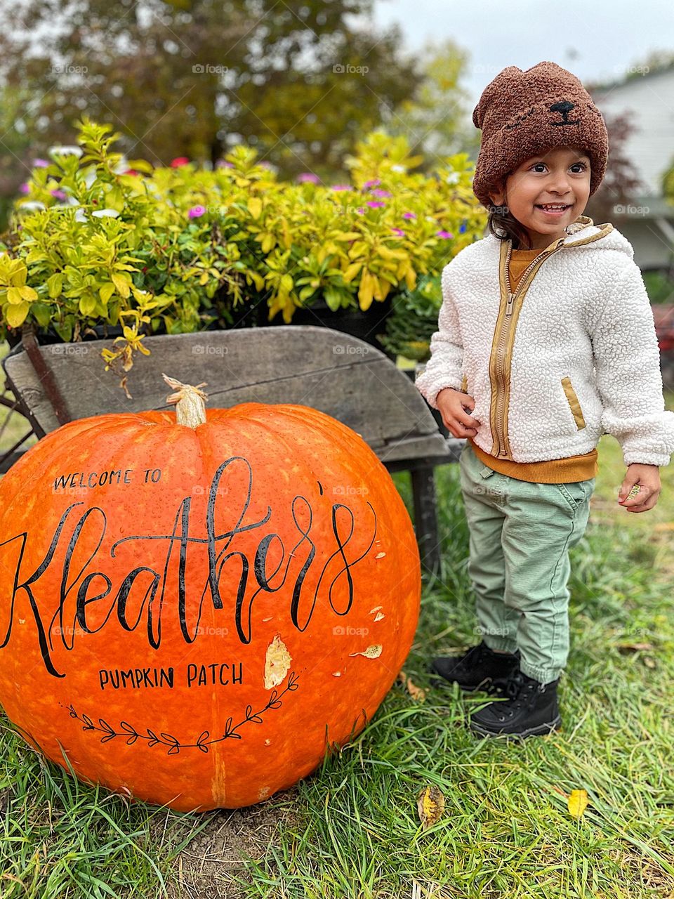 Toddler at the pumpkin patch, fall time activities, fun in the pumpkin patch, smiling for the camera, autumnal fun, kids enjoying pumpkins 