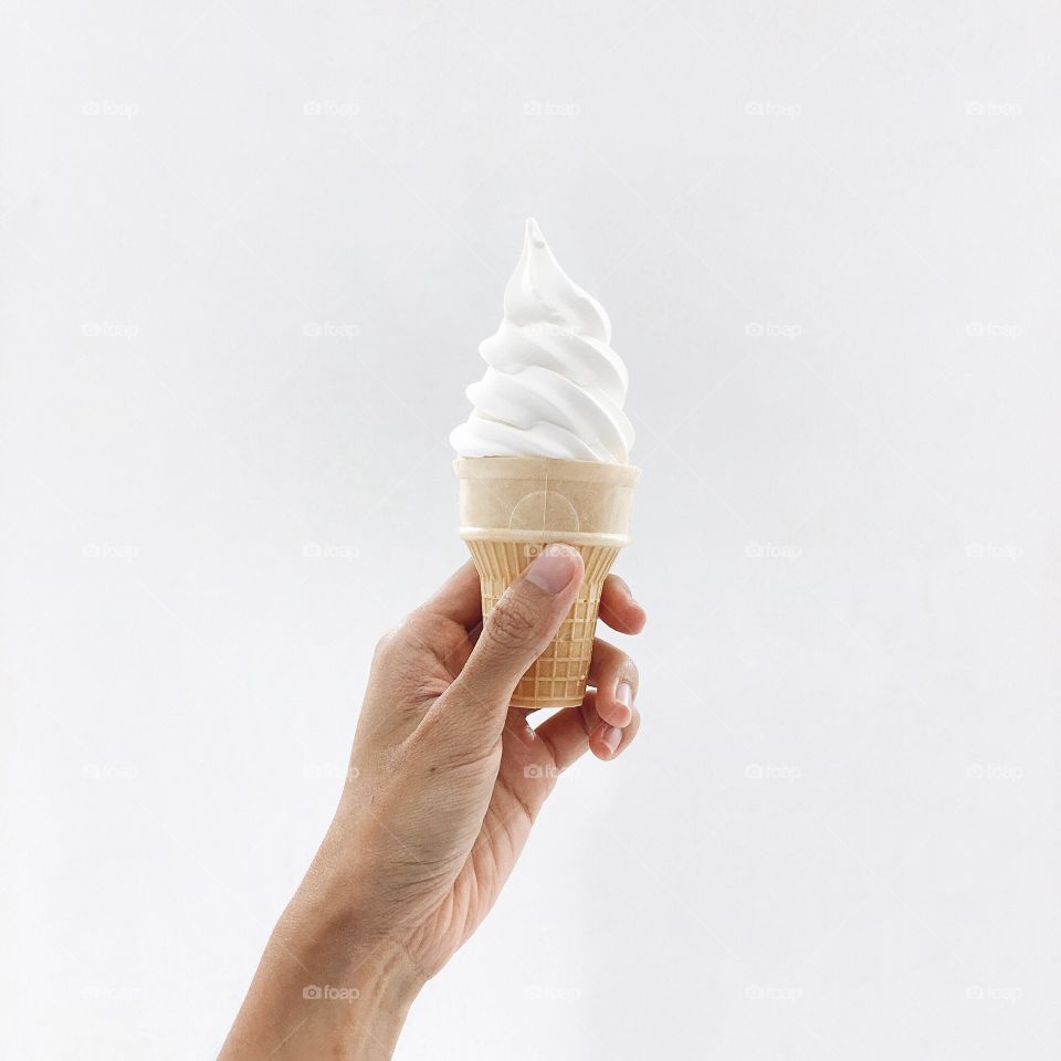 Hand holding ice cream against white background