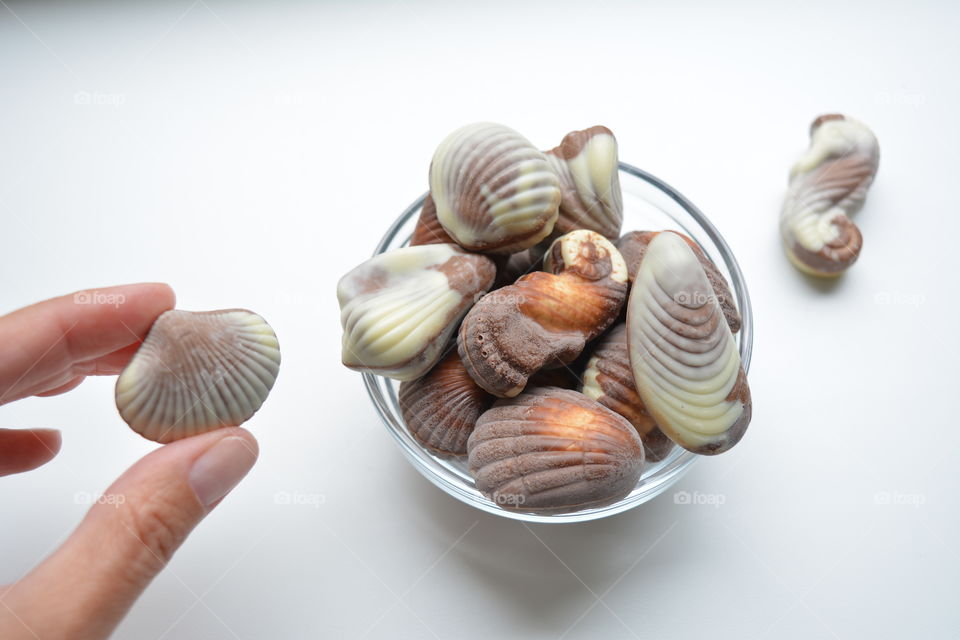 candy milk chocolate shells in hand eating tasty delicious food white background top view