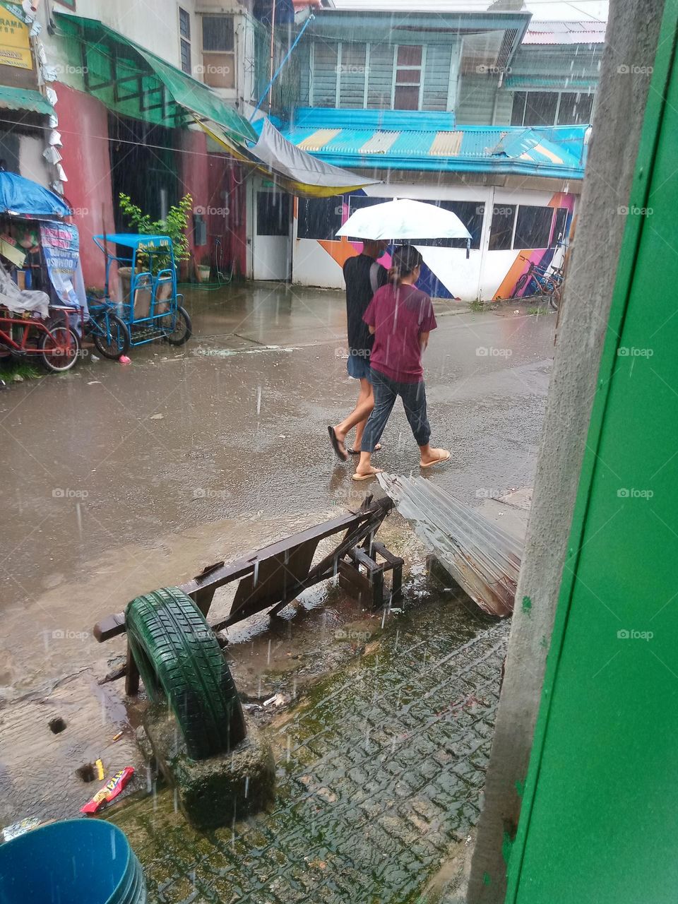 #LIQUIDSARECOOL,, AS THE RAIN STREAMS ON THE STREET,, AND TWO INDIVIDUALS ARE SHARING ON ONE UMBRELLA, WALKING ON THE WET ROAD