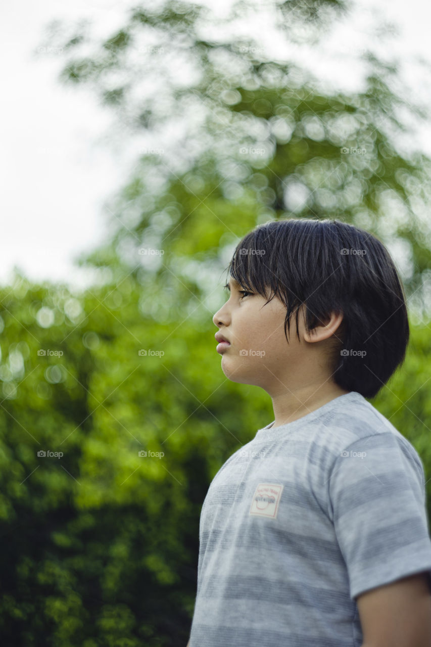 outdoor portrait of young eurasian boy on a blurry out of focus bokeh foliage background