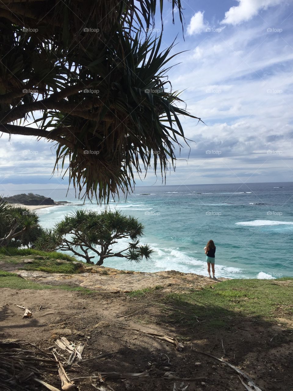 Girl standing on cliff overlooking ocean in Australia 