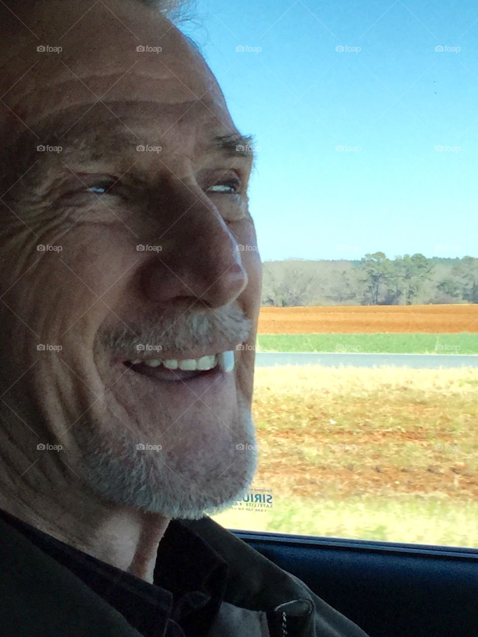 Funny guy driving with a chicklet gum sticking out of his toothy smile.